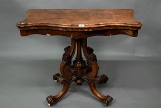 A Victorian walnut card table, the fold over serpentine top with baize lining, raise on moulded