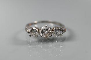 A diamond ring, the three graduated diamonds claw set with diamond set shoulders, white metal set