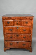 An early 18th century walnut chest of three short over three long graduated drawers, raised on