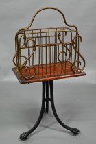 An antique cast iron, brass and mahogany revolving newspaper stand, raised on paw feet