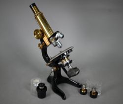 An Optca lacquered brass compound microscope with spare object lens and two spare subject lenses, 34