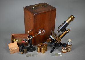 A lacquered brass microscope in case with magnifier on stand and other accessories, spare lenses etc