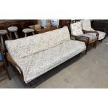 A mid 20th century teak three piece suite comprising a bed settee and two armchairs,