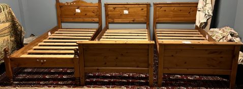 A pair of pine single beds together with another pine single bed