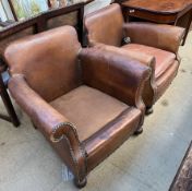 A pair of brown leather armchairs