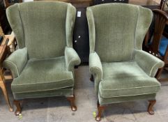 A pair of Parker Knoll upholstered wing back arm chairs on cabriole legs and pad feet