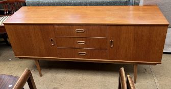 A mid 20th century teak veneered sideboard with two cupboards and three drawers on tapering legs,