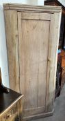 A 19th century pine standing corner cupboard, with a moulded cornice above a single panelled door,