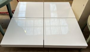 A white high gloss coffee table of square form with sliding top enclosing a storage compartment