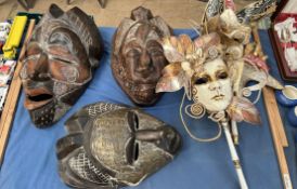 Three carved African masks together with two Venetian masks with carrying handles