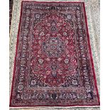 A red ground rug with a central medallion and floral spandrels with guard stripes,