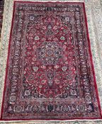 A red ground rug with a central medallion and floral spandrels with guard stripes,