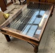 A modern hardwood coffee table with a glass and lattice metal top,