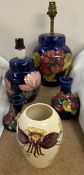 A Moorcroft table lamp decorated with flowers and leaves together with a smaller example,