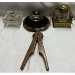 A brass and glass desk inkwell together with two other inkwells and a treen nut cracker