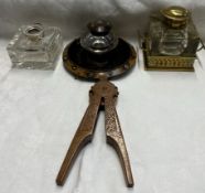 A brass and glass desk inkwell together with two other inkwells and a treen nut cracker