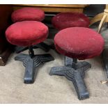 A set of four stools with circular pad seats on a trefoil cast iron base