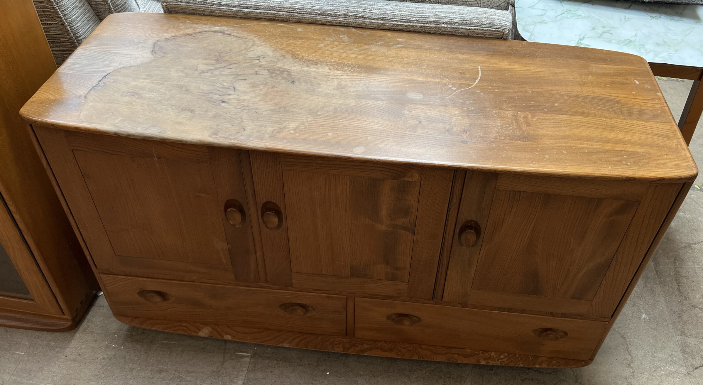 An Ercol light elm sideboard with three cupboards above two drawers on casters, 129.5cm wide x 75.