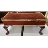 An upholstered footstool of rectangular form with a pad seat on shell capped cabriole legs and pad