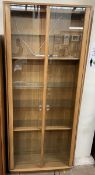 An Ercol light elm display cabinet with glazed doors and shelves,
