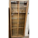 An Ercol light elm display cabinet with glazed doors and shelves,