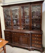 A George III style mahogany break front bookcase with a moulded cornice above four glazed doors