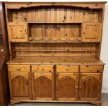 A modern pine dresser with a moulded cornice, shelves and two cupboards,