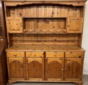 A modern pine dresser with a moulded cornice, shelves and two cupboards,
