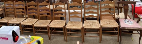 A set of eight early 20th century oak ladder back dining chairs with rush seats on tapering legs