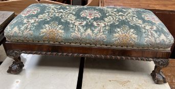 An early 20th century walnut footstool with an upholstered pad top on leaf carved cabriole legs and