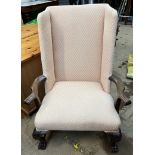 A 20th century wing back arm chair with outswept arms,
