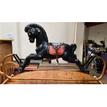 A black rocking horse of moulded construction on a metal base