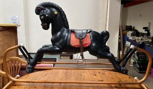 A black rocking horse of moulded construction on a metal base