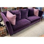 A large purple upholstered Colin and Hayes three seater settee on bracket feet