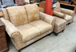 A brown leather two seater settee together with a matching arm chair and foot stool