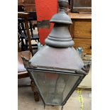 A large copper gas lantern with a shaped finial above a leaf capped tapering body