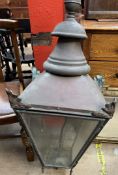 A large copper gas lantern with a shaped finial above a leaf capped tapering body