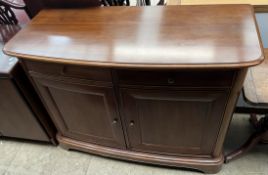 A modern mahogany sideboard with a bowed top above two drawers and two cupboards on bracket feet