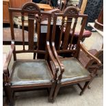 A pair of oak elbow chairs with a carved back above a drop in seat on square tapering legs and