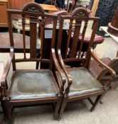 A pair of oak elbow chairs with a carved back above a drop in seat on square tapering legs and