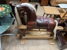 A rocking horse with a leather saddle on an oak base