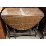 A 20th century oak gateleg dining table with an oval top and drop flaps on barley twist legs