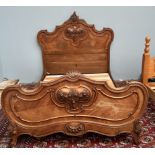 A French walnut double bed with a carved head and foot boards