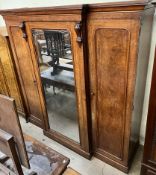 A Victorian mahogany triple wardrobe with a central mirrored door flanked by a pair of cupboard