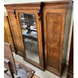 A Victorian mahogany triple wardrobe with a central mirrored door flanked by a pair of cupboard