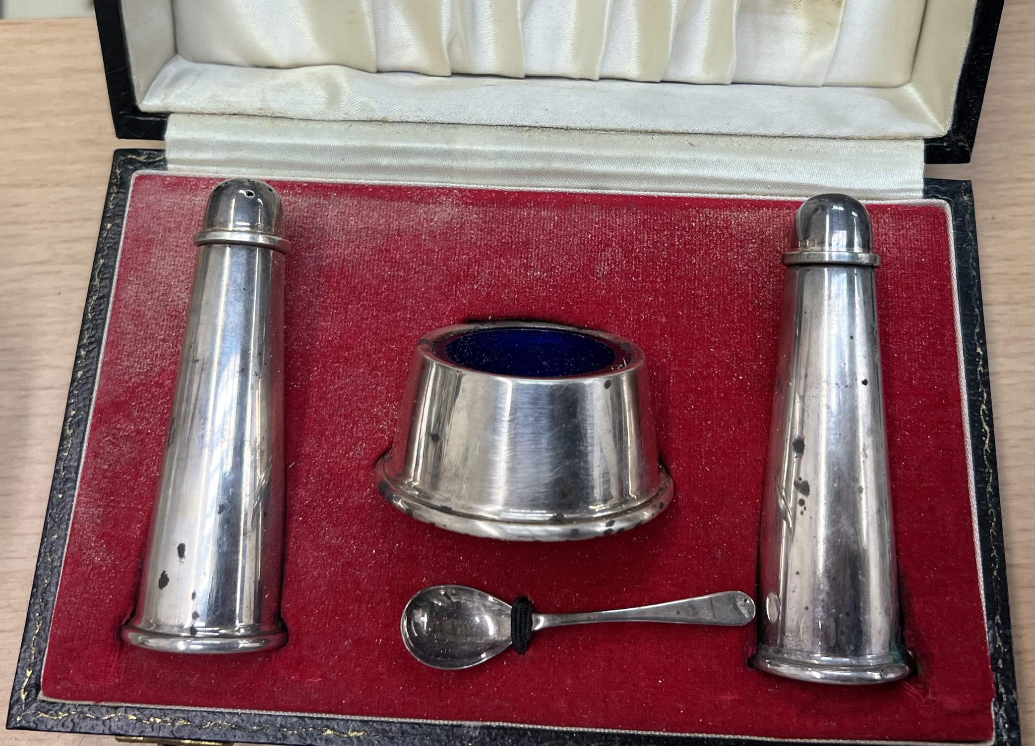 A cased silver cruet set together with white metal topped dressing table pots,