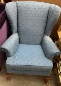 An upholstered wing back armchair on cabriole legs