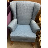 An upholstered wing back armchair on cabriole legs