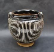 A twin handled vase in the style of a Tz'u-chou jar with white slip ribs and a dark brown glaze,