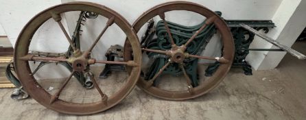 A pair of cast iron wheels together with three cast iron bench seat ends and cast iron table ends